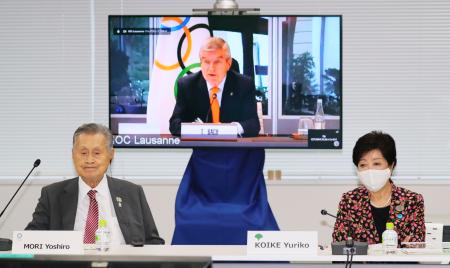 オンライン形式で行われた合同会議であいさつするＩＯＣのバッハ会長（奥）。手前左は東京五輪・パラリンピック組織委員会の森喜朗会長、同右は東京都の小池百合子知事＝２４日午後、東京都中央区（代表撮影）