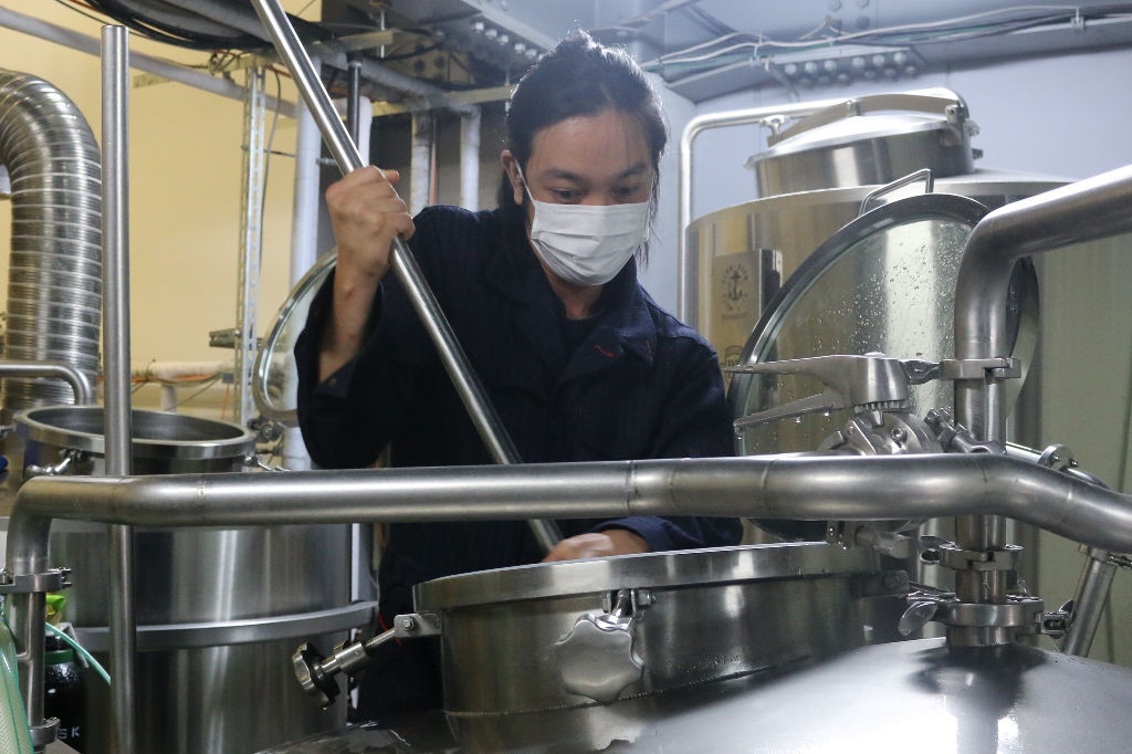 麦汁を攪拌する阿久沢健志さん＝１１月上旬、沼津市の柿田川ブリューイング