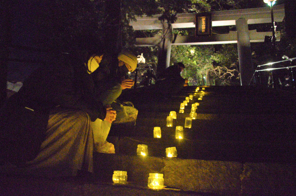 復興を祈りキャンドルに手を合わせる参加者＝３１日午後、熱海市の伊豆山神社