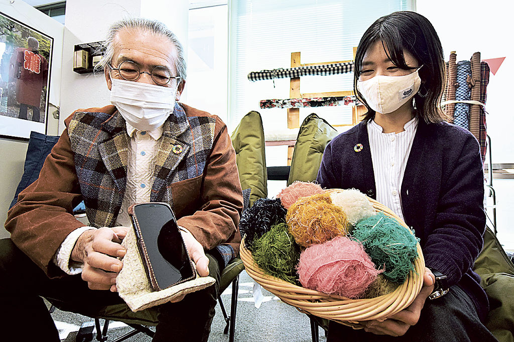 布みみを手にする加藤満さん（右）。左は布みみを中綿に使用したスマートフォンスタンド＝１１月下旬、浜松市中区の遠州織物工業協同組合