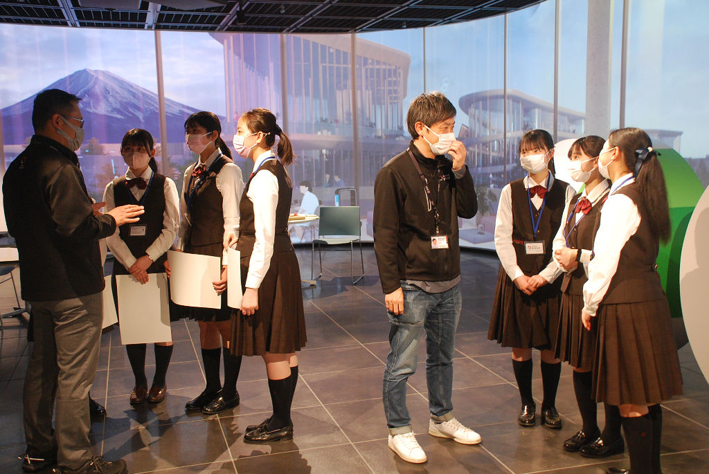 ウーブン・シティのイメージ画像が映し出された壁の前で説明を受ける生徒たち＝東京都中央区のウーブン・プラネット・ホールディングス