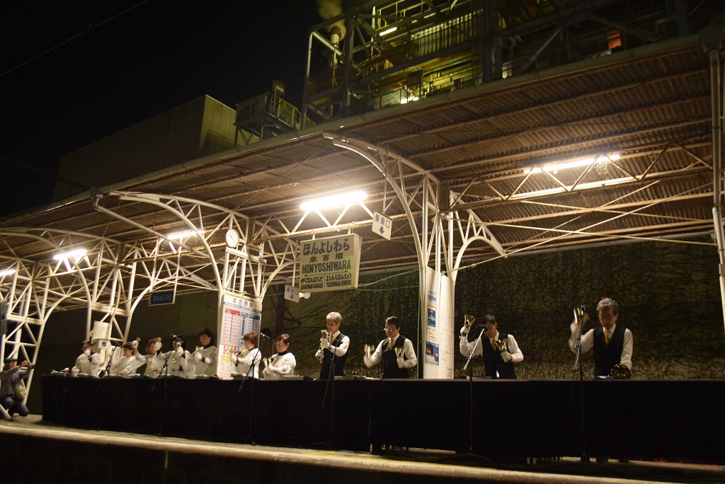 工場を背に演奏を繰り広げる「ＭＡＵハンドベルリンガーズ」＝７日、富士市の岳南鉄道本吉原駅