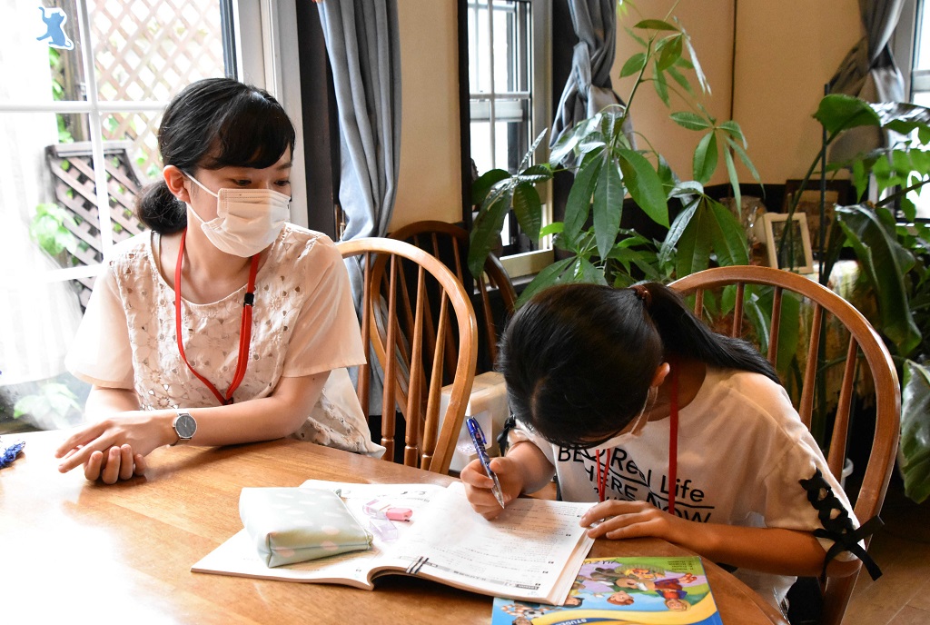 閉店後の喫茶店で学生と一緒に勉強に取り組む児童＝焼津市内 