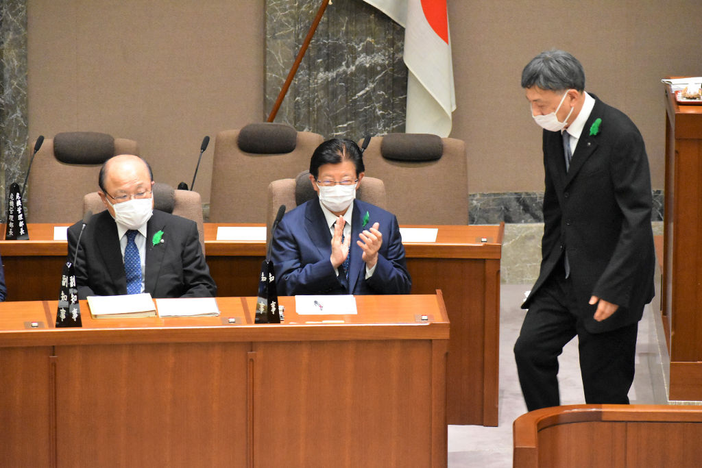 副知事退任あいさつを終えた難波喬司氏（右）に拍手する川勝平太知事（中央）。左は出野勉副知事＝２０日午後、静岡県議会