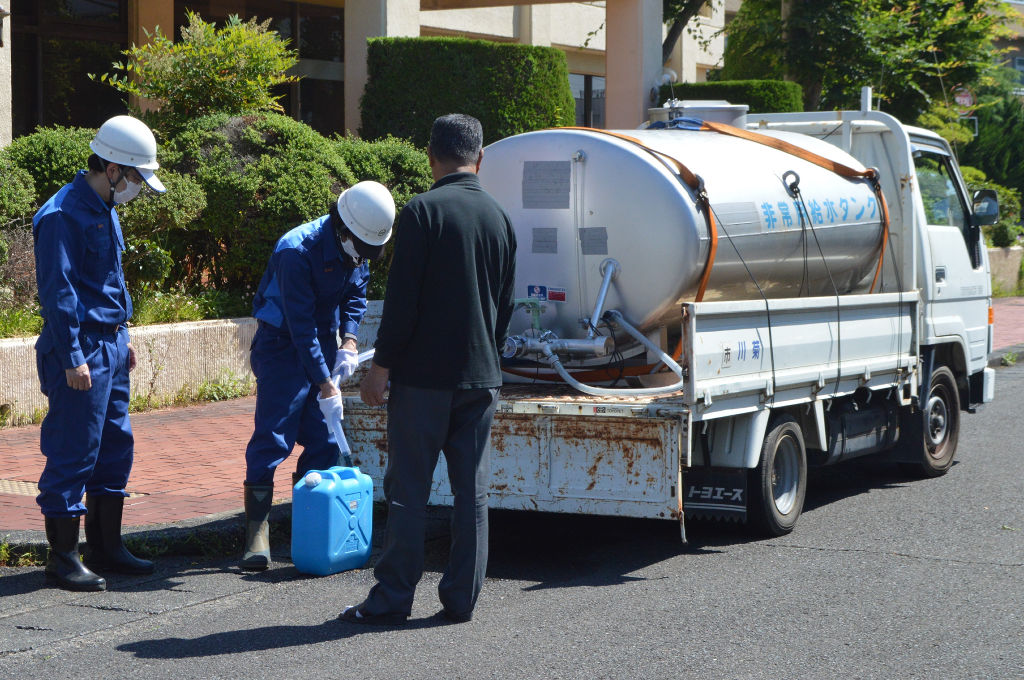 給水車から水を配る菊川市職員（中央）。断水の影響は長期化した＝２３日、同市役所
