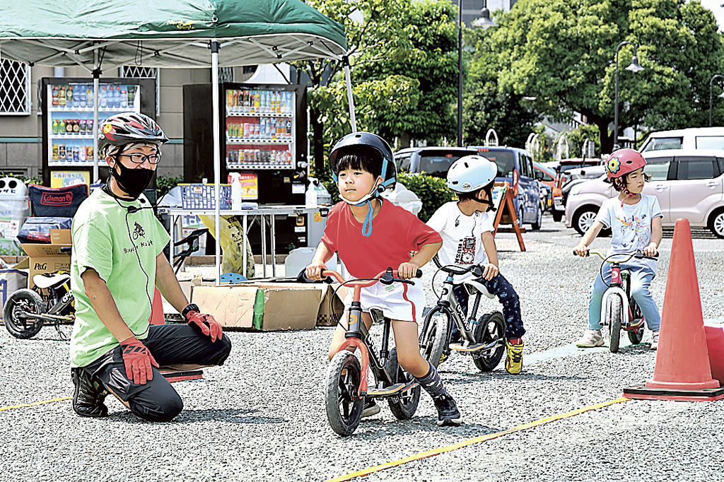 大塚さん（左）の指導でキックバイクを運転する参加者＝富士市中央公園駐車場