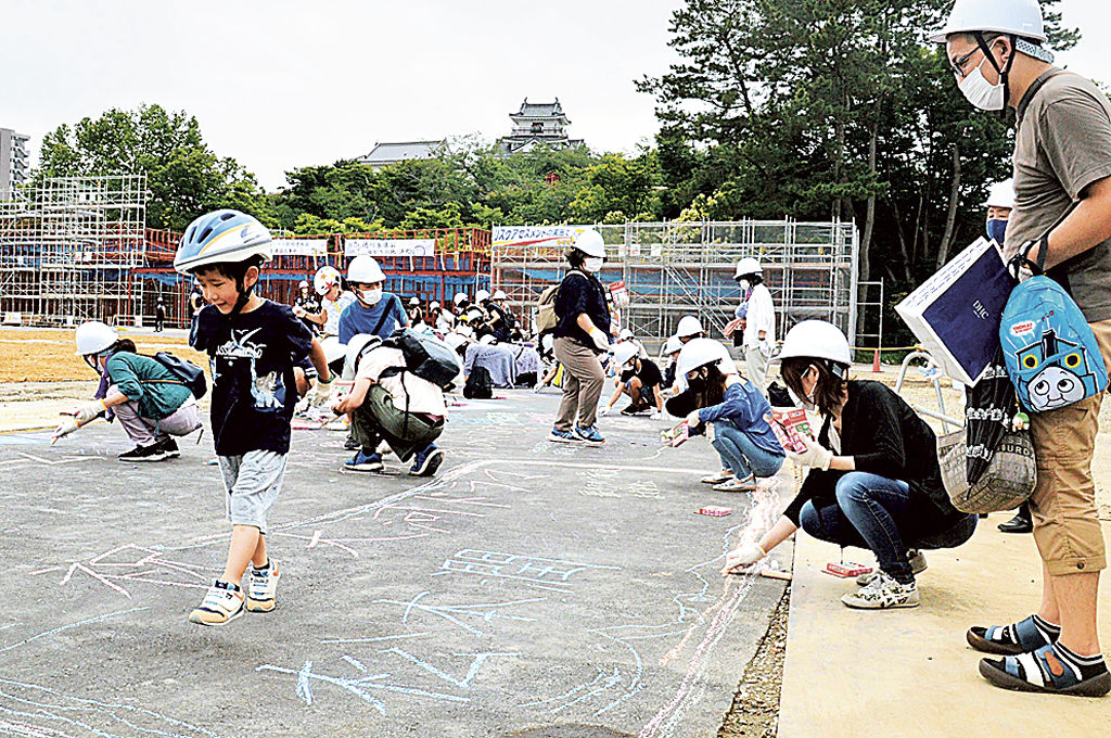 舗装面に出演者への応援メッセージを書く参加者=浜松市中区の大河ドラマ館建設地