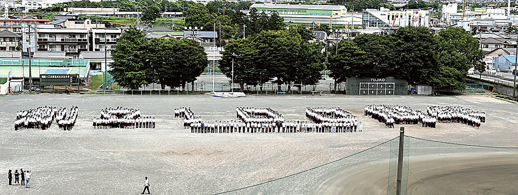 整列して「創立１００周年」の文字を作る生徒ら＝富士市の富士高