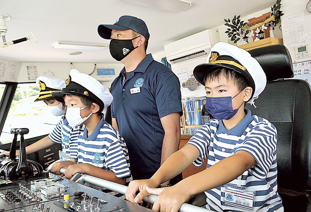 操舵室で船長の業務を体験する３人＝熱海市沖（写真の一部を加工しています）