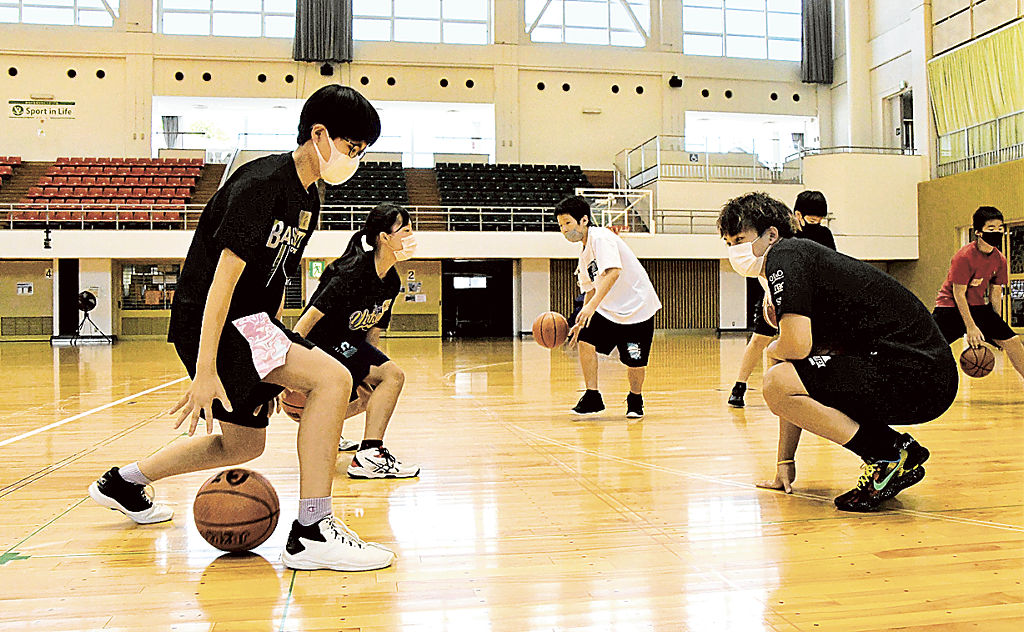 プロ選手の指導を受けながらドリブルを練習する児童たち＝静岡市葵区の市中央体育館
