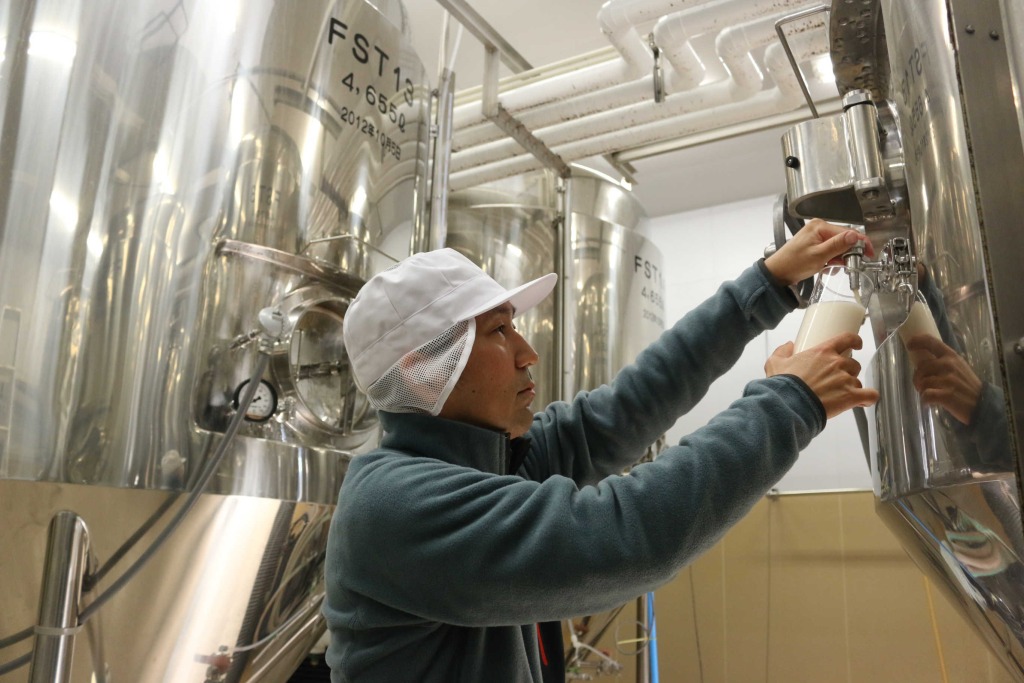 タンクから発酵中のビールを取り出す木村岳司さん＝１６日、函南町の酪農王国オラッチェ