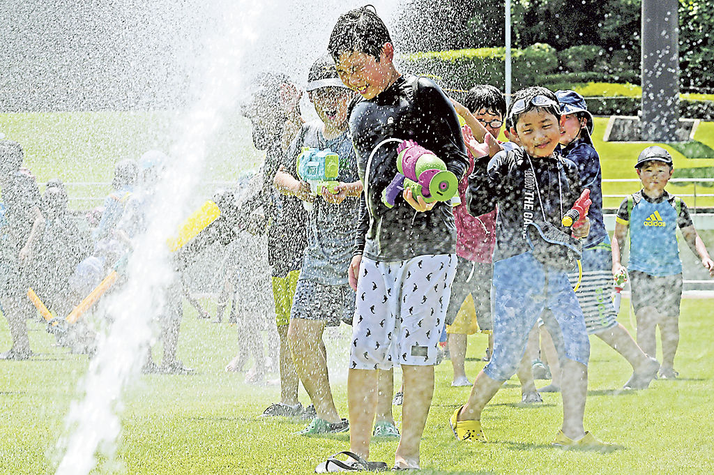 スプリンクラーから噴き出す水に歓声を上げる子どもたち＝静岡市葵区の西ケ谷総合運動場