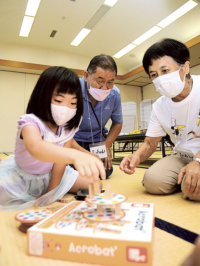 アナログゲームで遊ぶ子どもらの様子を見る稲津達義さん（中央）。地域への恩返しをしようと活動に励む＝７月下旬、浜松市浜北区