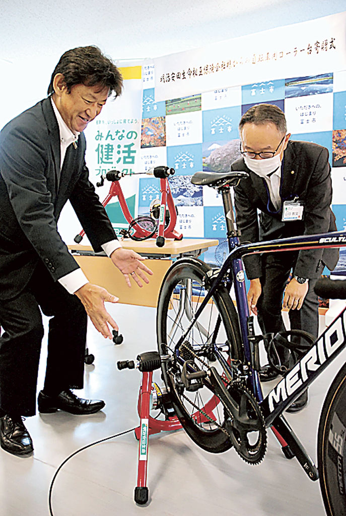 自転車用ローラー台の機能などを説明する今田支社長（左）＝富士市の市サイクルステーション