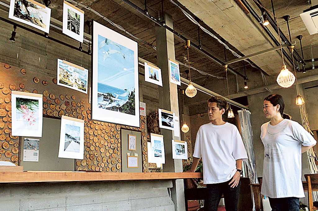 風景写真に水彩画を重ね合わせた作品を眺める富岡さん（右）とＹＵＴＡさん＝熱海市伊豆山のあいぞめ珈琲店