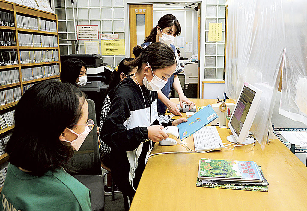 司書の指導を受けながらカウンターで本を確認する子どもたち＝長泉町民図書館