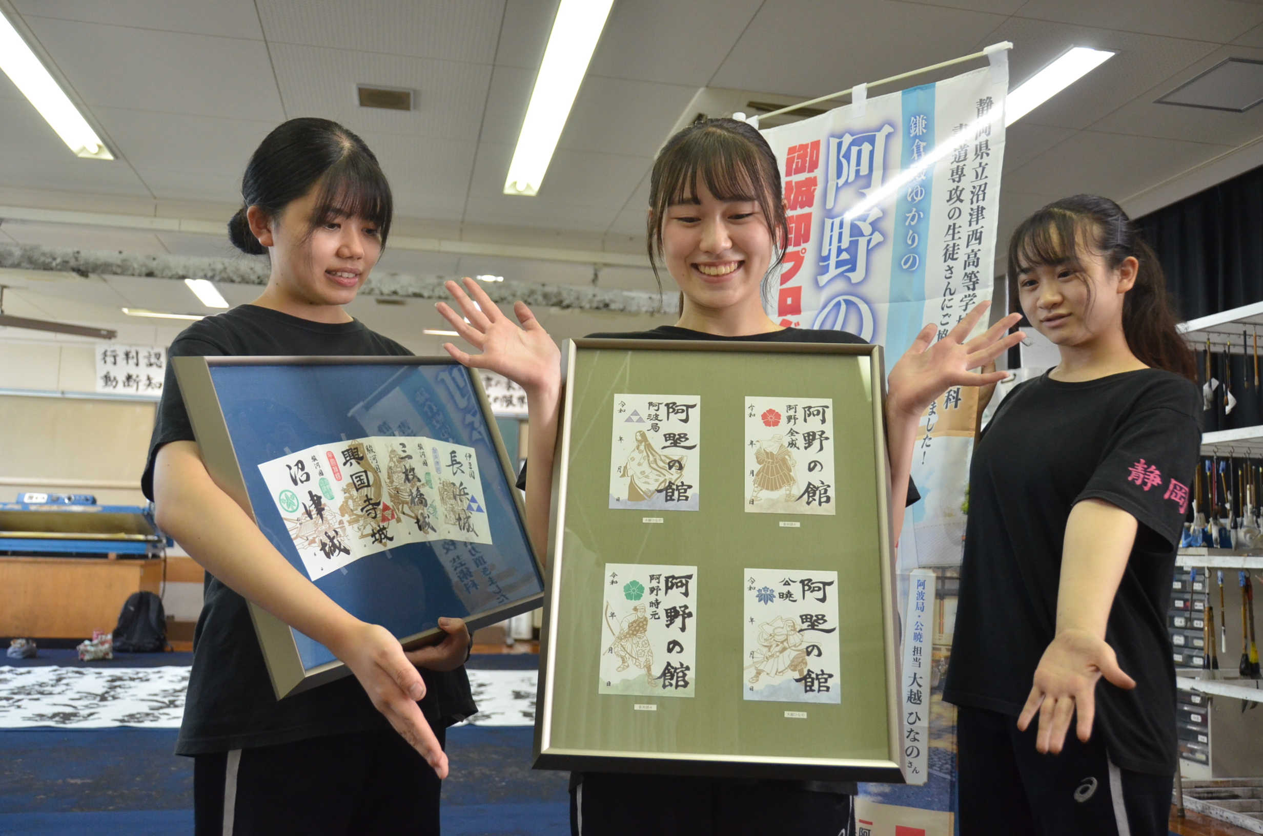 沼津西高芸術家書道専攻の生徒が作製した御城印を掲げる音渕胡々さん（中央）