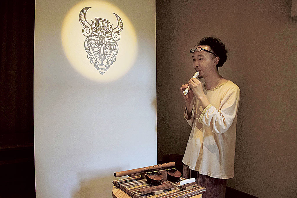 鹿の骨から制作した笛を吹く神さん＝浜松市中区の鴨江アートセンター