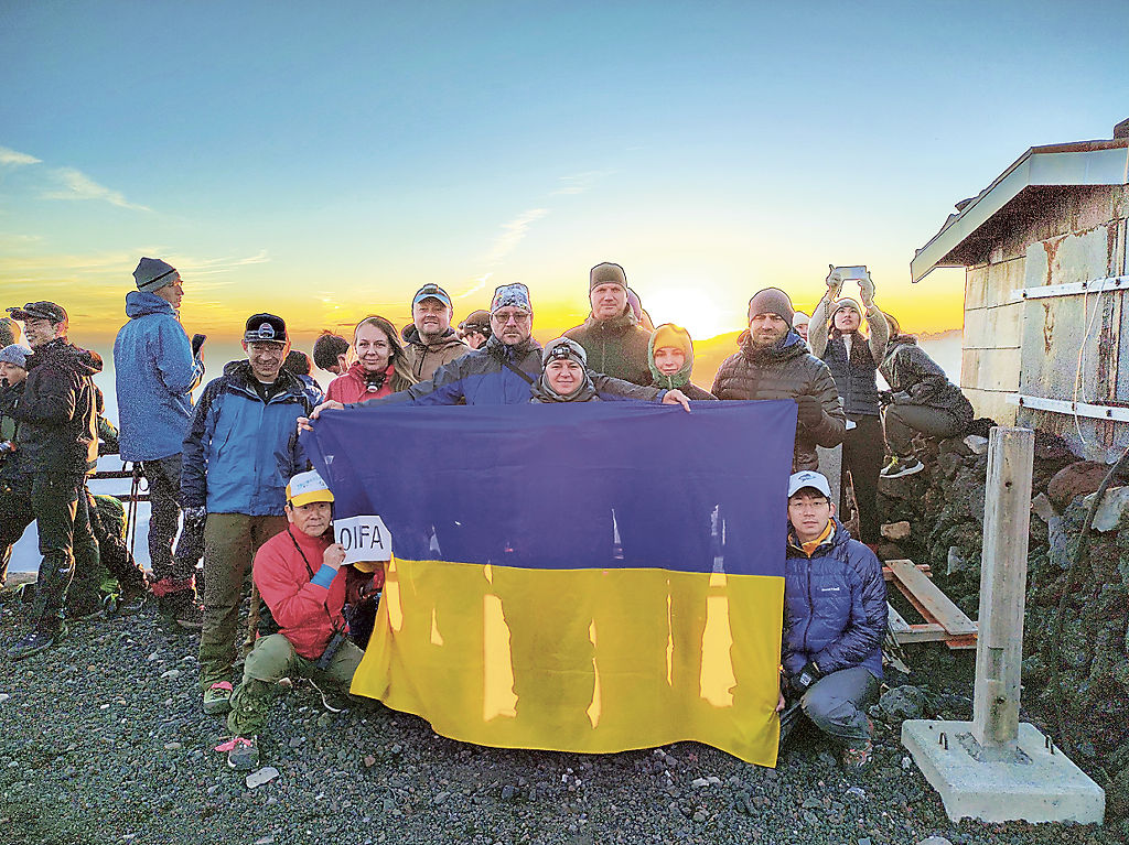 富士山頂でウクライナ国旗を掲げ、平和を祈る在日大使館員ら＝２４日午前５時１０分ごろ（小山町提供）