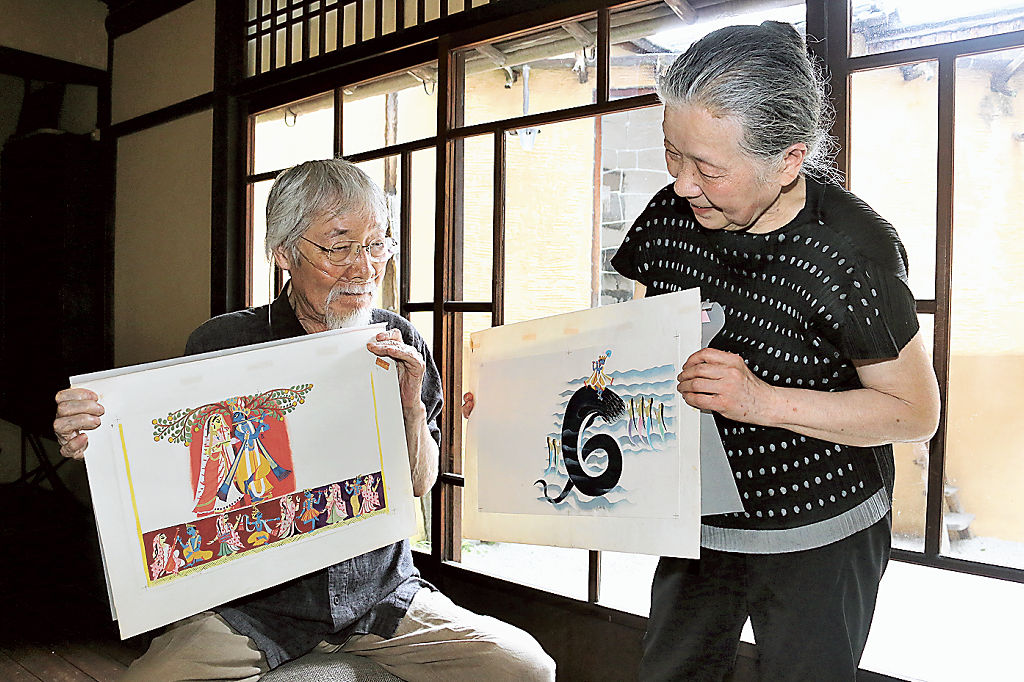 絵本の原画を手にする秋野等さん（左）。右は妻章子さん＝８月中旬、京都市
