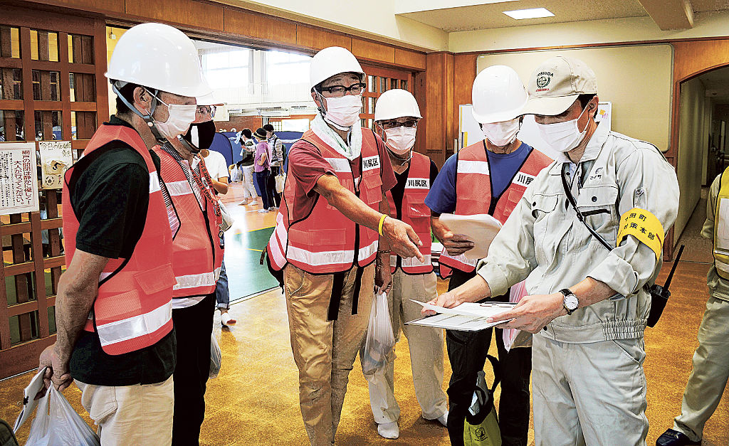 感染の疑いのある避難者などへの対応方法を確認する町職員（右）と自主防災会のメンバー＝４日午前、吉田町の中央小