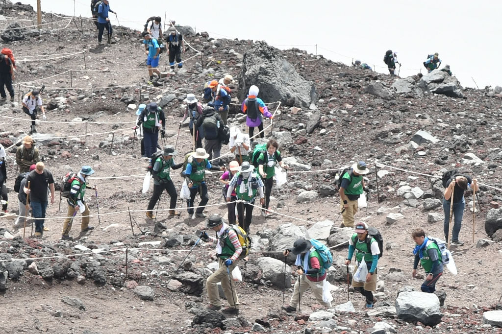 緑色のビブスを着てごみを拾いながら歩く社員たち＝富士山の富士宮口９合目付近