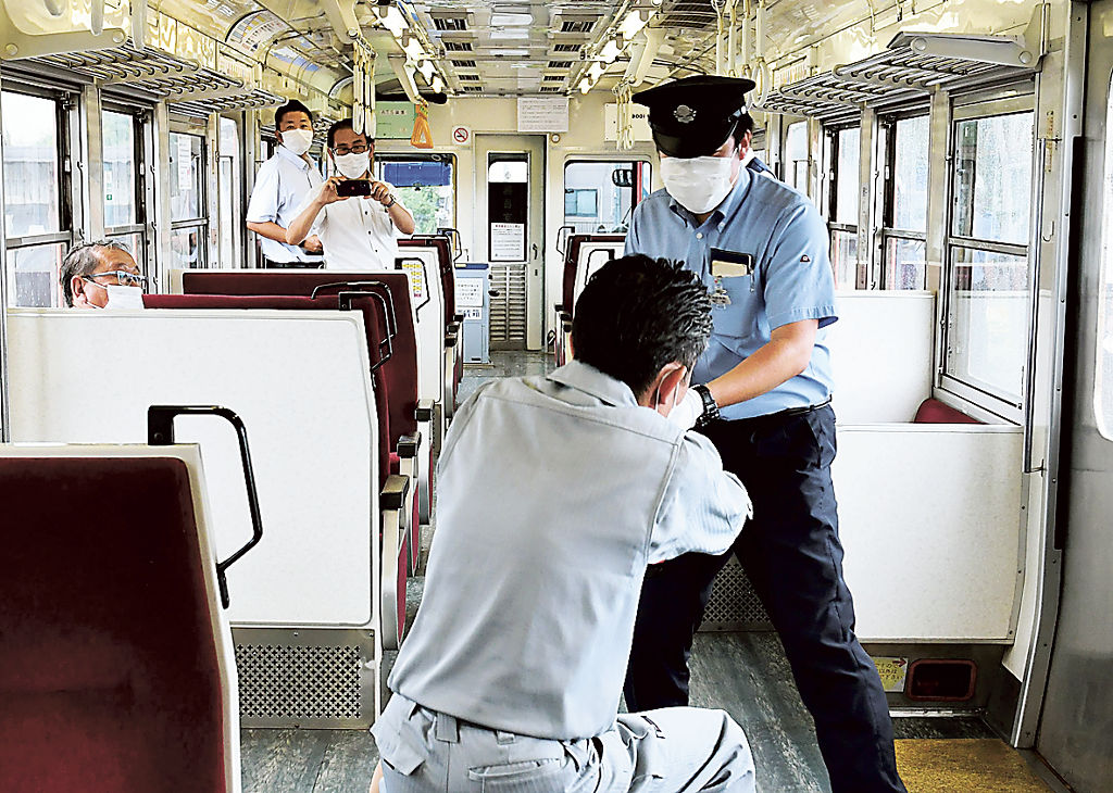 犯人役の男に対処する乗務員（右）＝富士市の岳南江尾駅
