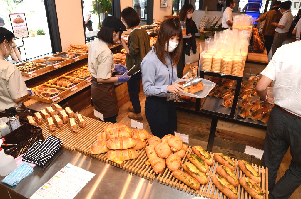 プレオープンイベントで、ずらりと並んだパンを購入する関係者ら＝浜松市浜北区のハウオリベーカリー