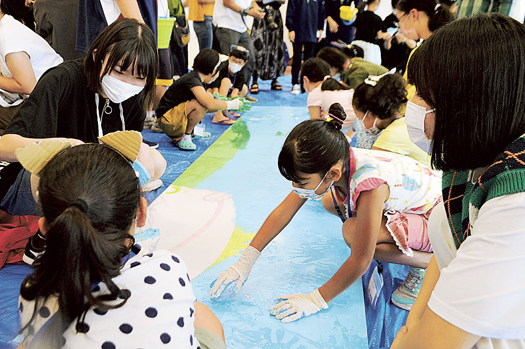 イベントの看板に絵を描く小学生と高校生＝菊川市のプラザきくる