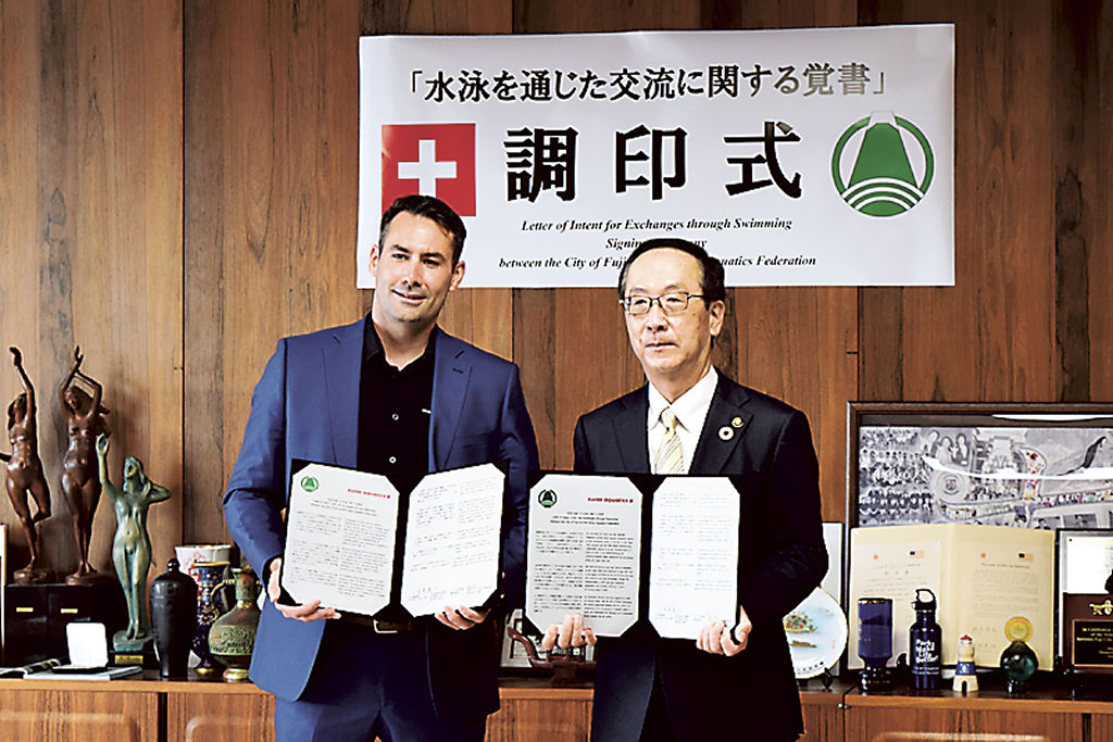 署名を交わしたバック監督（左）と小長井市長＝富士市役所
