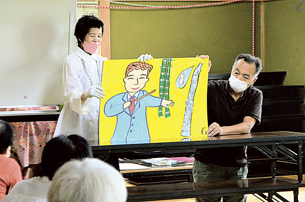赤堀庄太郎さんを題材にした紙芝居を披露する山田さん（左）＝菊川市加茂