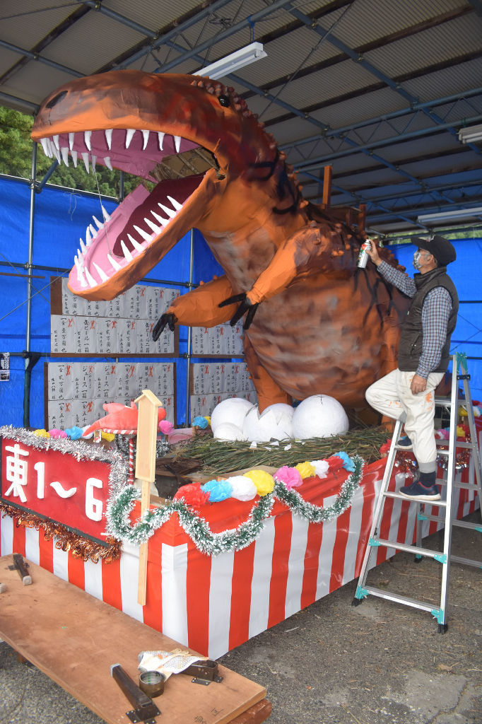 恐竜が目を引く山車の仕上げ作業に取り組む殿岡さん＝川根本町千頭