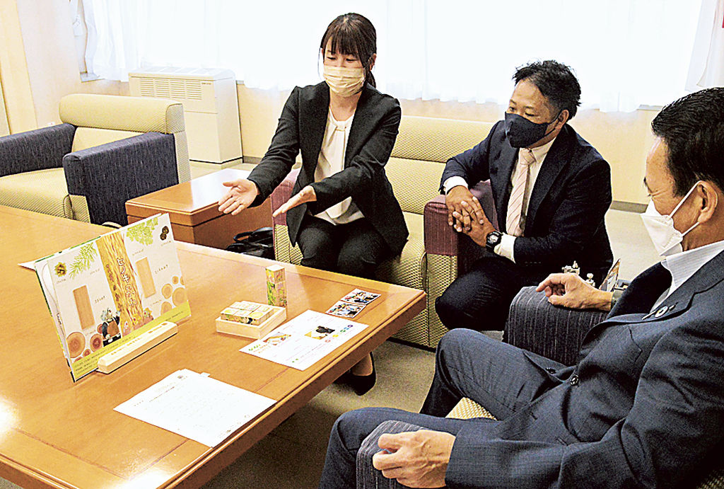 鈴木市長（右）に絵本の内容を説明する永田社長（中央）と妻の友美さん＝浜松市役所