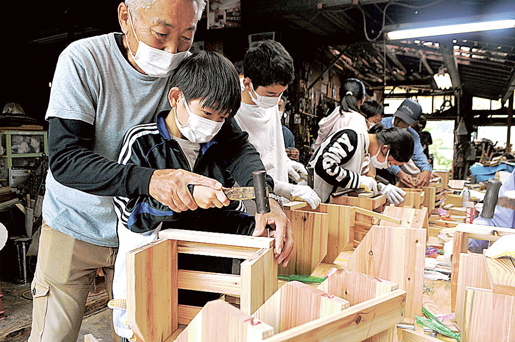 真剣な表情で本箱づくりに取り組む児童＝藤枝市のスギヤマ建築