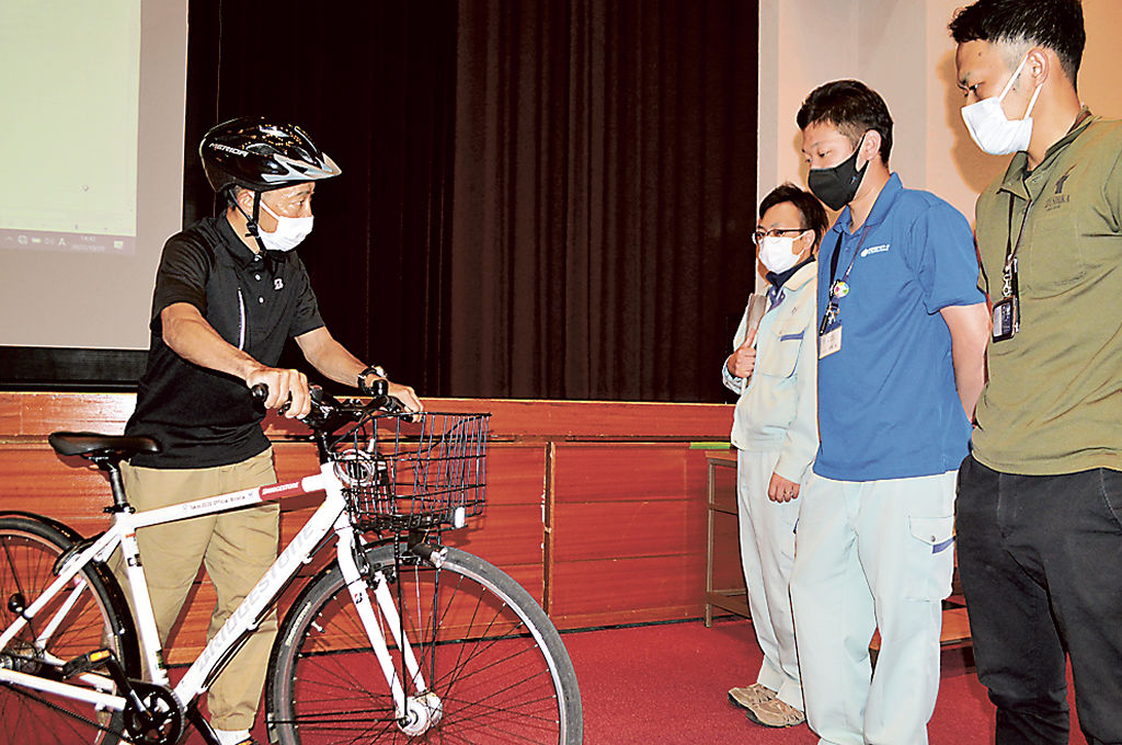 市職員に自転車の点検方法を実演する飯島さん（左）＝伊豆市民文化ホール