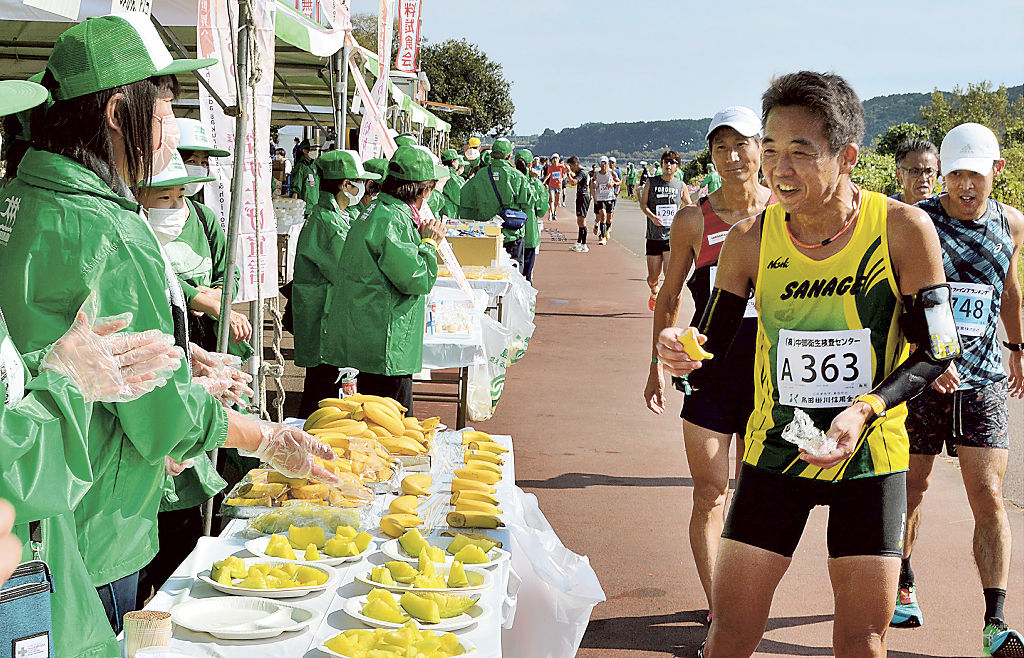 食事や飲料を提供し、ランナーにエールを送るボランティア（左側）＝島田市の大井川河川敷マラソンコース「リバティ」