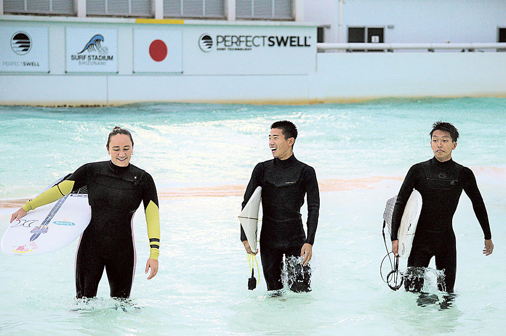 サーフィンを通じて交流を深めるムーア選手（左）と相良高の生徒ら＝牧之原市の静波サーフスタジアム