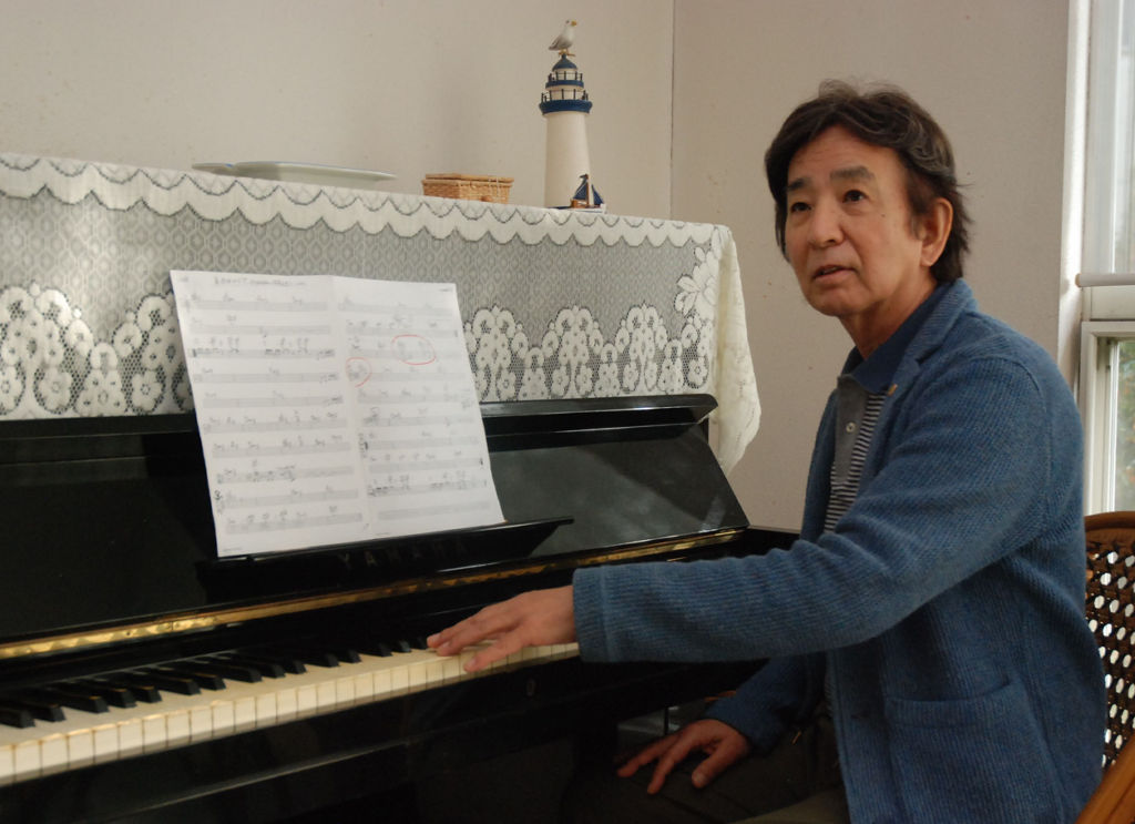 楽曲の譜面を確認する林哲司さん。バンド演奏や作曲活動の原点は高校時代にある＝三島市内