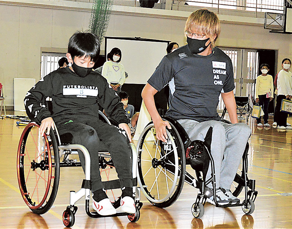 車いすの試乗体験をする児童に指導する池崎選手（右）＝浜松市中区の佐藤小