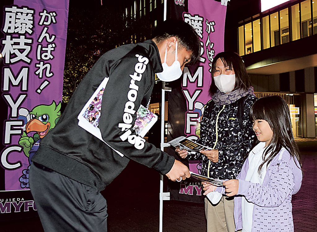 渡辺選手（左）からホーム最終戦への来場を呼びかけるチラシを受け取る親子＝ＪＲ藤枝駅南口