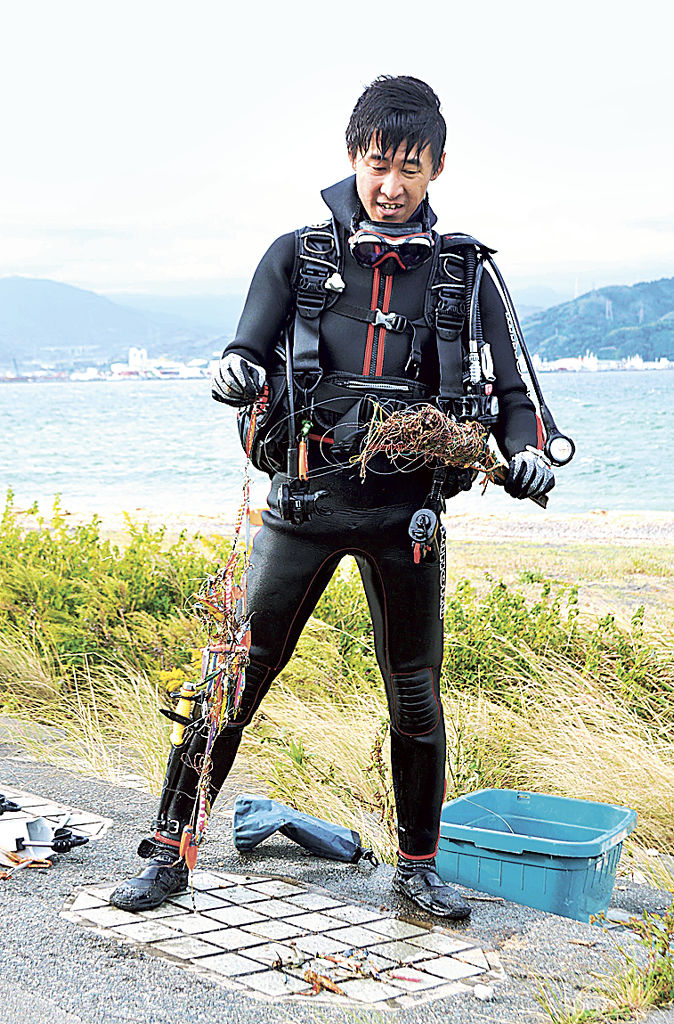 海底から回収したルアーなどを手にする土井さん＝静岡市清水区三保の真崎海岸