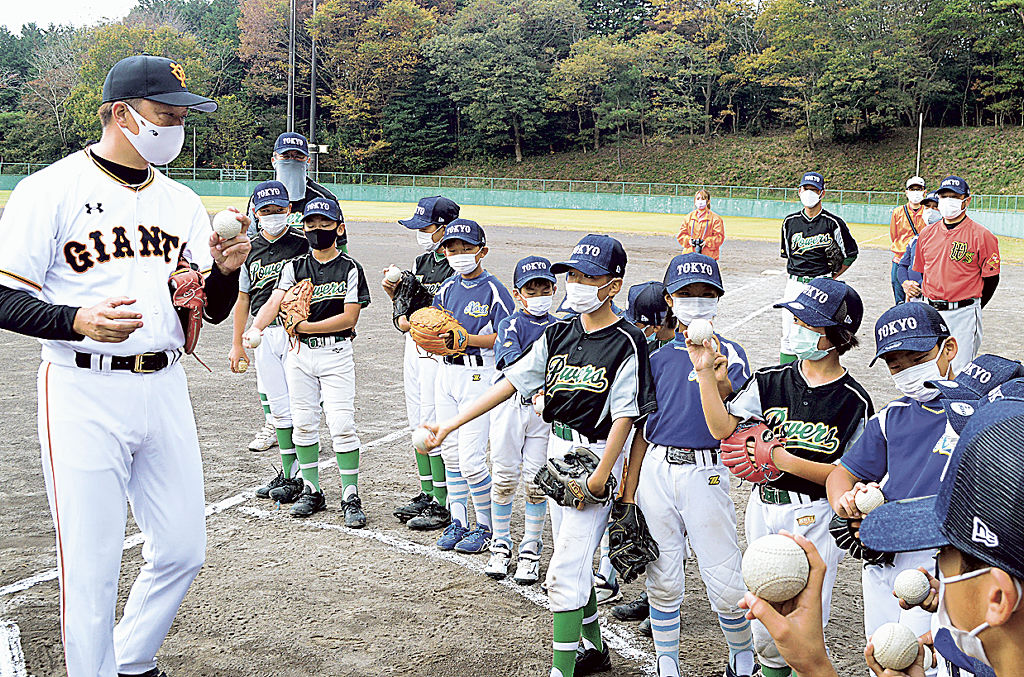 岡島さん（左）から球の握り方を教わる参加者＝伊豆の国市のさつきが丘公園野球場