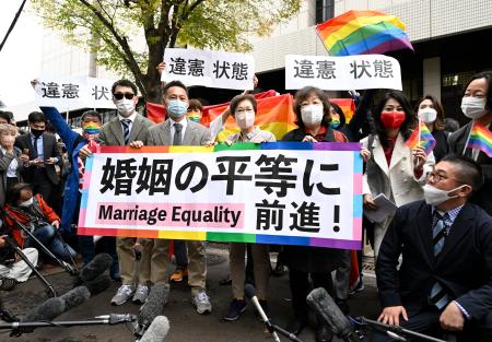 同性婚を巡る訴訟の判決後、東京地裁前で「婚姻の平等に前進！」と書かれた紙を掲げる原告ら＝３０日午後