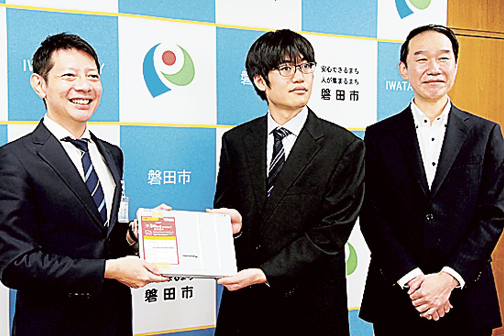 草地市長（左）にリユースパソコンを手渡す須田さん（中央）と水口社長＝磐田市役所