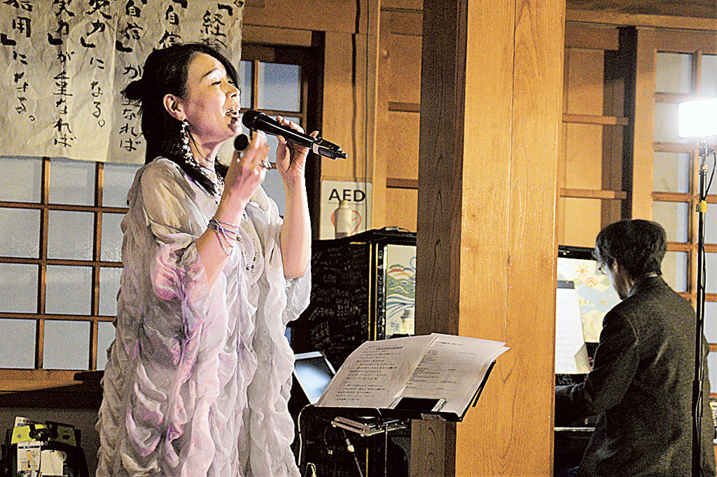 “寺ピアノ”の演奏で歌う鈴木さん＝湖西市の龍谷寺