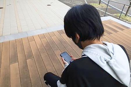 スマートフォンでゲームをする男子高校生（写真と本文は関係ありません）
