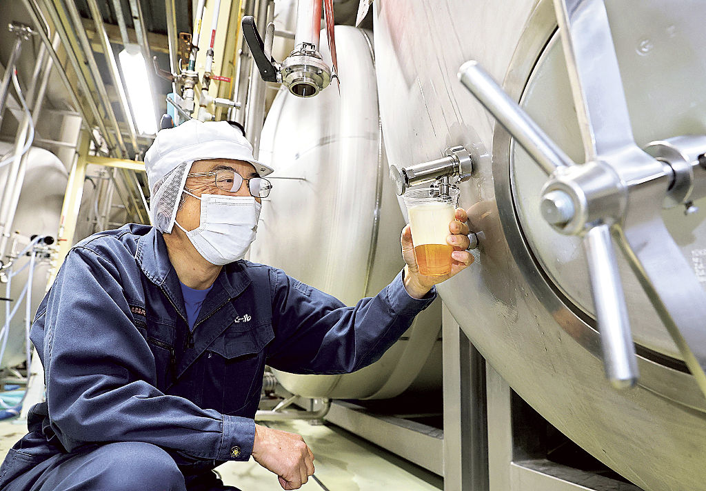 熟成タンクから注がれたビールの品質を確かめる佐々木正幸工場長＝新潟市西蒲区