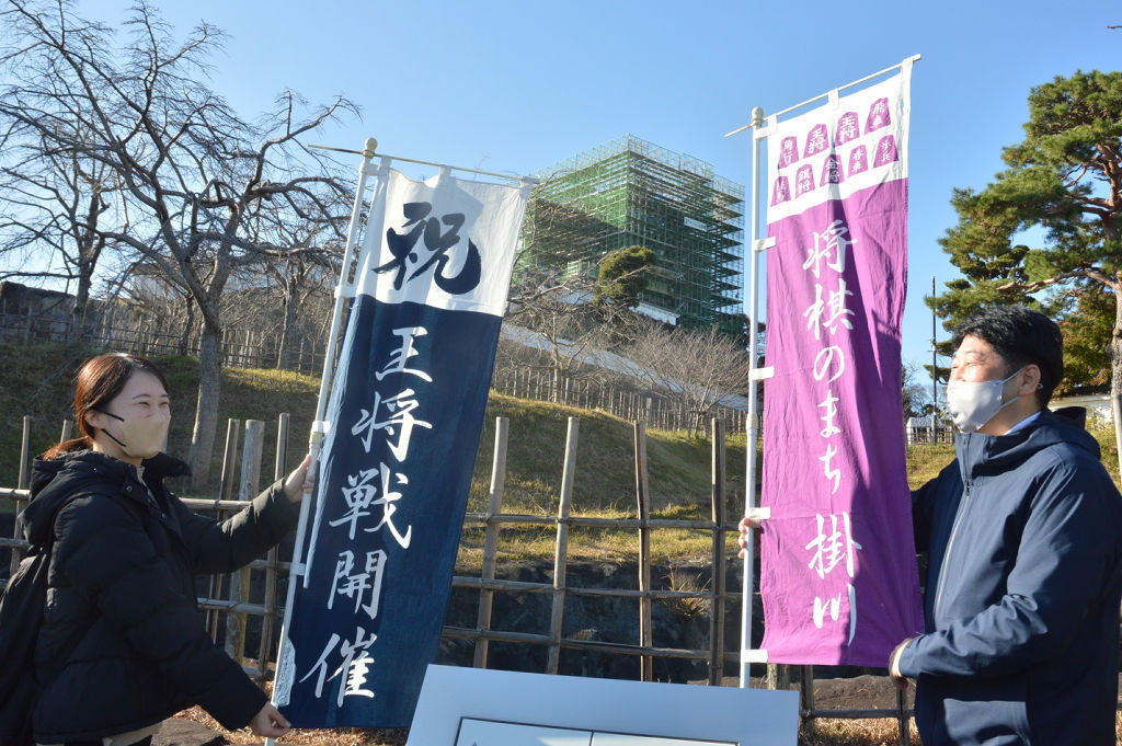 天守閣が覆われた掛川城の城下にのぼり旗を設置する職員＝１２月上旬、掛川市中心部