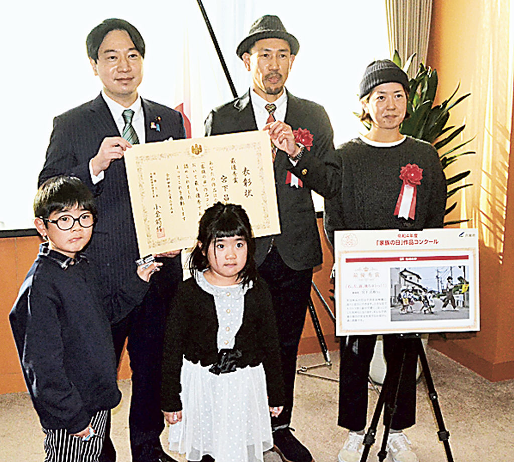 小倉少子化対策担当相（左）から表彰状を受け取る宮下さんと家族＝内閣府