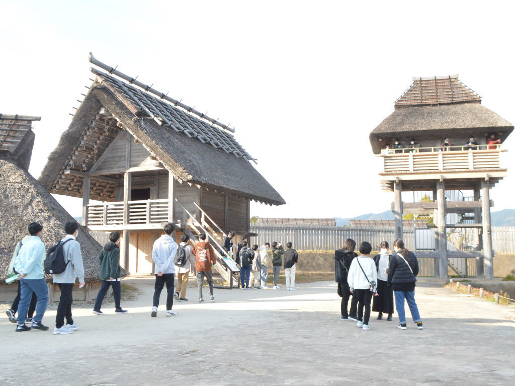 復元された物見やぐらや祭殿を見学する駿河総合高の生徒ら＝昨年１２月、佐賀県吉野ケ里町の吉野ケ里歴史公園